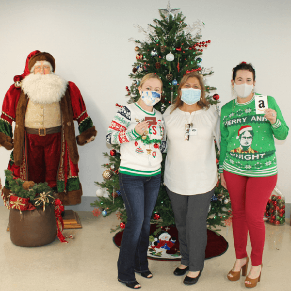 Three women posing in front of a Christmas tree