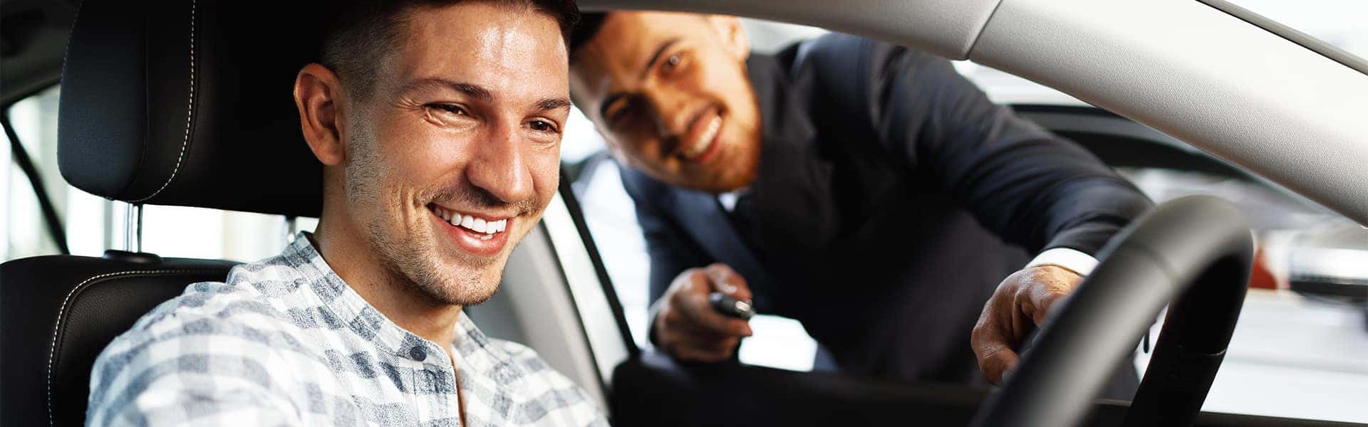 Trading in/selling your vehicle with Bennett Maserati of Allentown | Customer Sitting Inside Vehicle While Sales Advisor Shows Them Ammenities of Vehicle