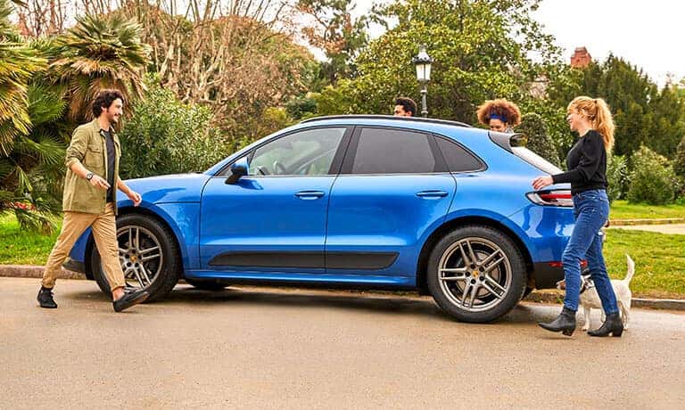 Friends getting into a 2021 Porsche Macan parked by the curb