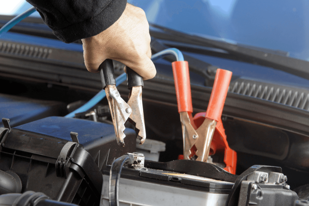 Person Disconnecting Jumper Cables From a Car Battery Close-Up