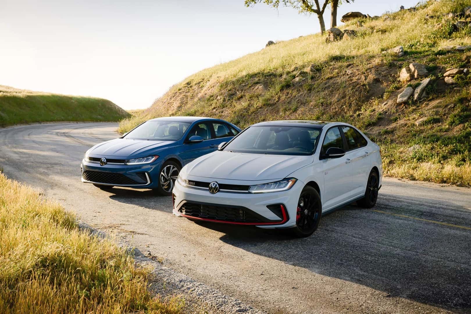 Two Fashionable And Reliable Volkswagen Jettas, Parked On A Road Winding Around A Hill