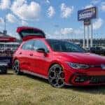 2026 Volkswagen Golf GTI rear hatch open in a Kansas Speedway tailgate lot on a sunny fall afternoon
