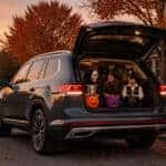 2026 Volkswagen Atlas with open liftgate on an Olathe street at dusk during Halloween season, children in costumes nearby