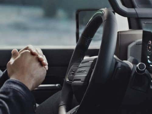 2024 Hummer EV SUV close up view of man in driver seat with hands off wheel
