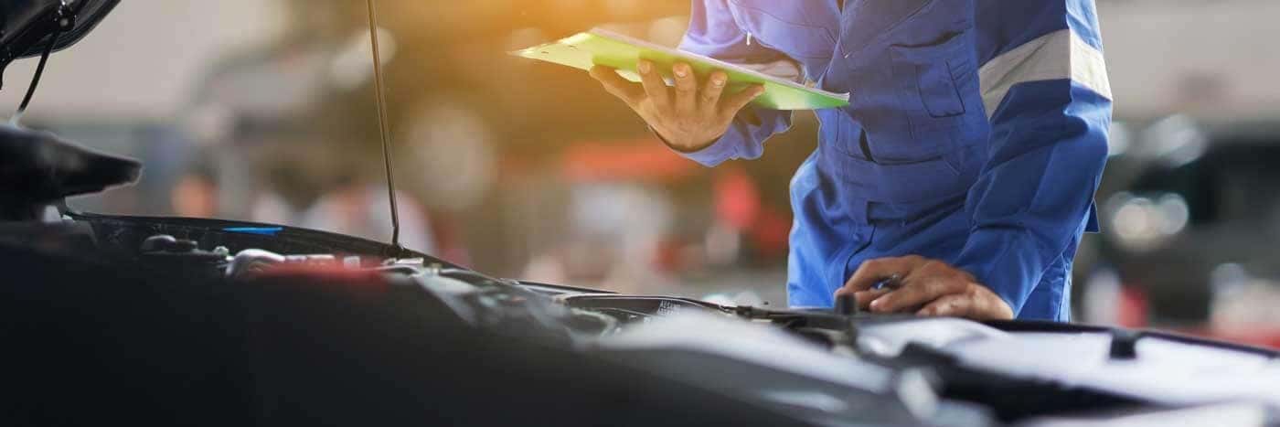 View of a service tech standing over an engine with a checklist