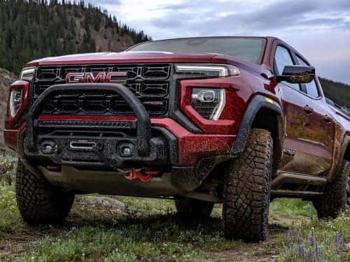 2025 GMC Canyon parked on a grassy mountain covered in mud