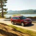 A red 2017 Chevy Traverse is shown passing a lake on the way to 'sell my car'.