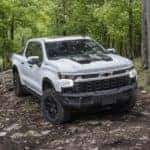 A white 2023 Chevy Silverado ZR2 Bison is shown on a trail in the woods after visiting a Birmingham Chevy dealership.