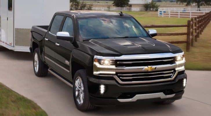 A black 2018 Chevy Silverado 1500 is shown towing a trailer.