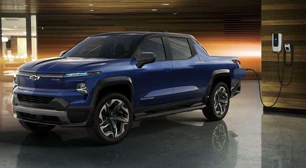 A blue 2024 Chevy Silverado EV is shown charging.