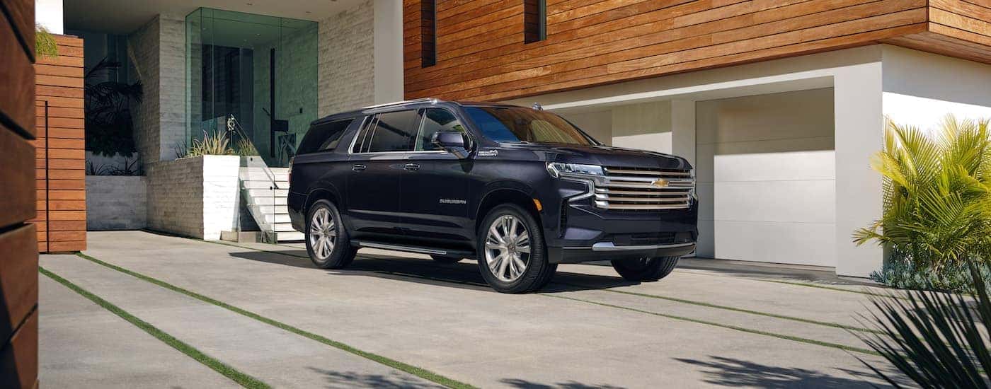 A blue 2023 Chevy Suburban is shown from the side parked in front of a building after leaving a Chevrolet dealer.