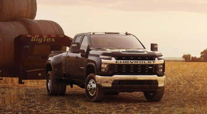 A black 2023 Chevy Silverado 3500 HD is shown parked in a field towing.
