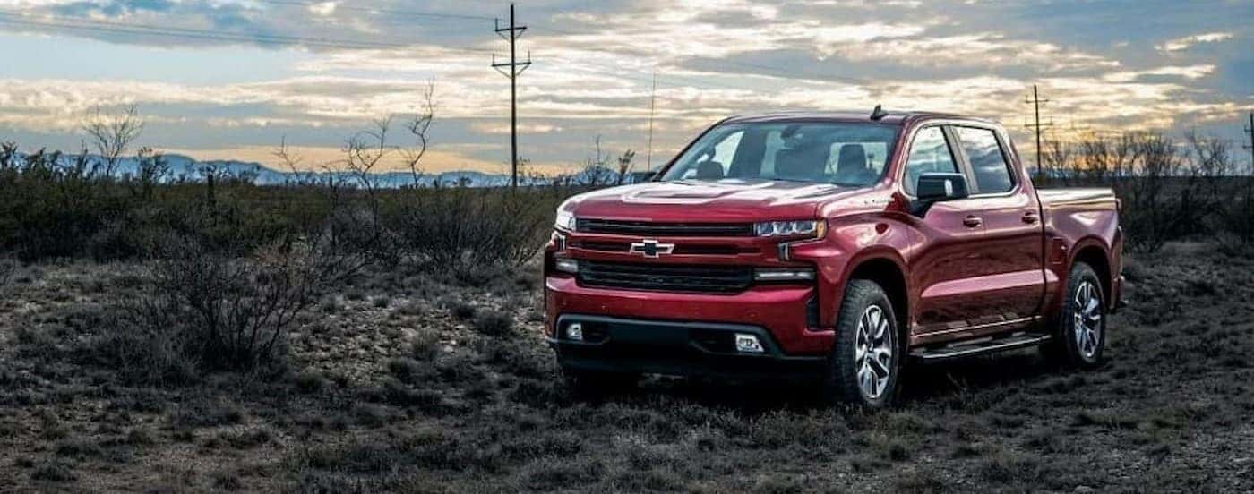 A red 2023 Chevy Silverado 1500 RST is shown parked near a field.
