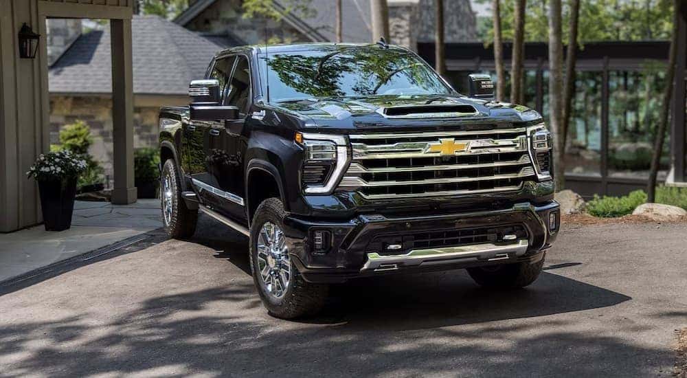 A black 2024 Chevy Silverado 3500HD High Country is shown parked near a house.