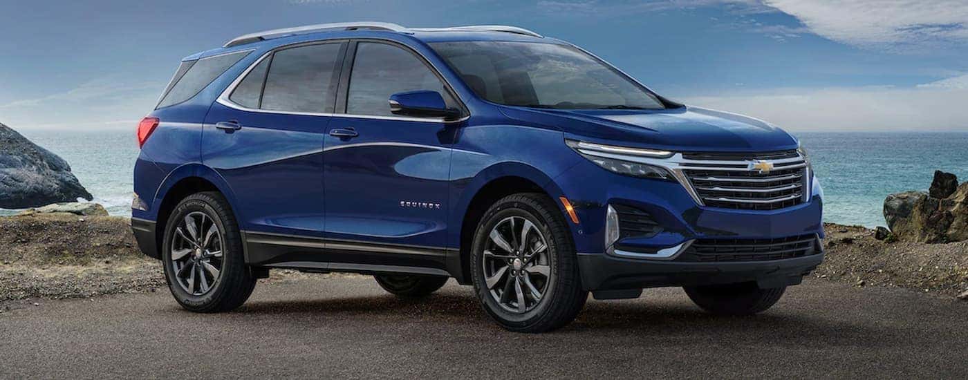 A blue 2022 Chevy Equinox is shown parked near an ocean.