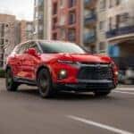 A red 2019 Chevy Blazer RS is shown driving on a city street after looking at used Chevy SUVs for sale.