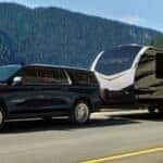 A popular used Chevy Suburban for sale, a black 2023 Chevy Suburban High Country, is shown towing a trailer.