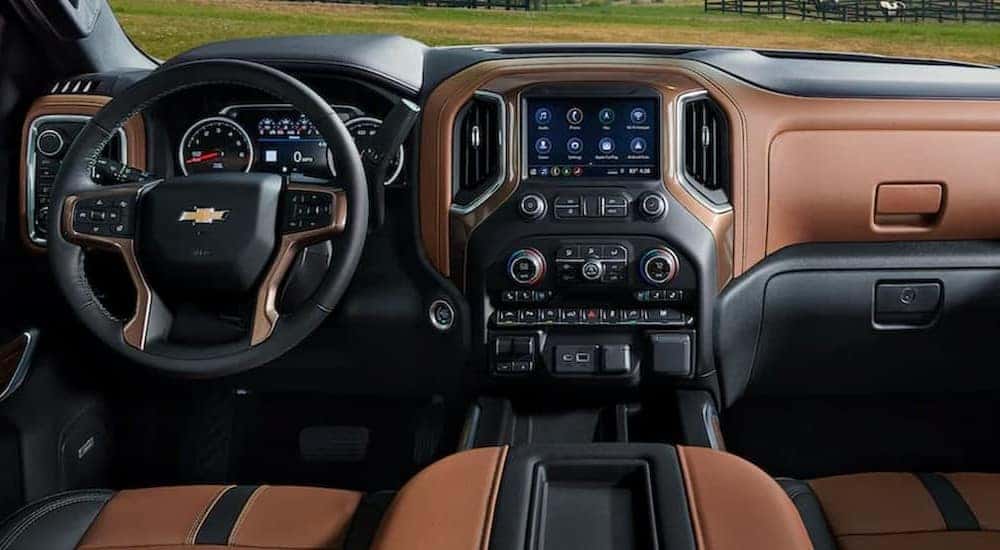 The black and brown interior and dash of a 2021 Chevy Silverado is shown.