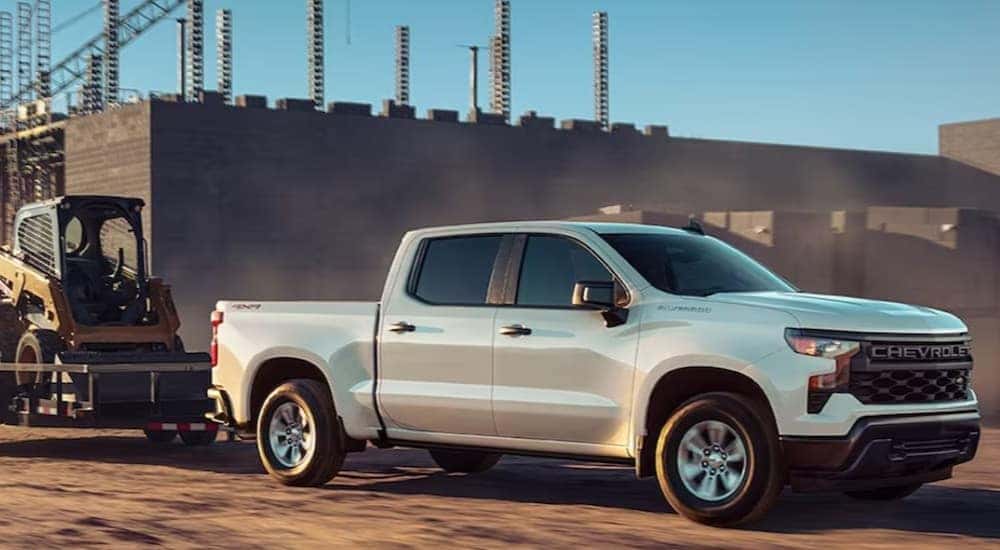 A white 2024 Chevy Silverado 1500 WT is shown towing a trailer.