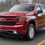 A red 2019 Chevy Silverado 1500 for sale near Bessemer driving past water.