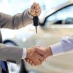 A car salesman is shown handing car keys to customer.