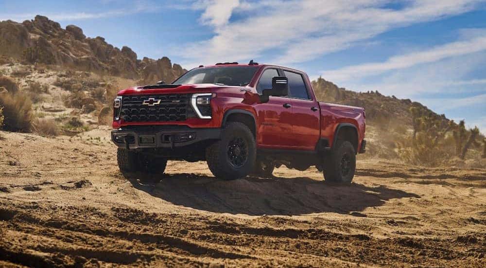 A red 2024 Chevy Silverado 1500 ZR2 Bison is shown parked on dirt.