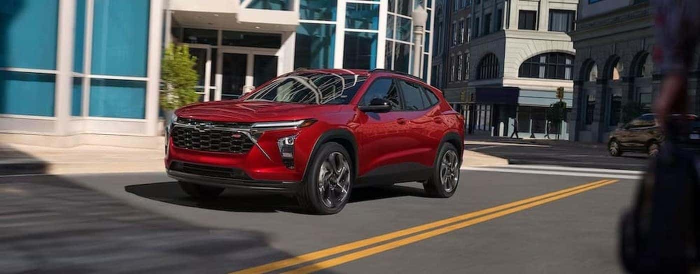 A red 2024 Chevy Trax RS is shown driving near a crosswalk.