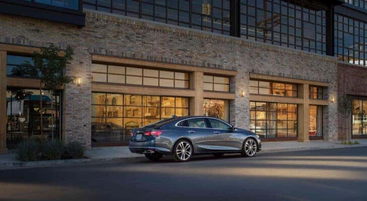 A grey 2021 Chevy Malibu is shown from the side after leaving a used car dealer.
