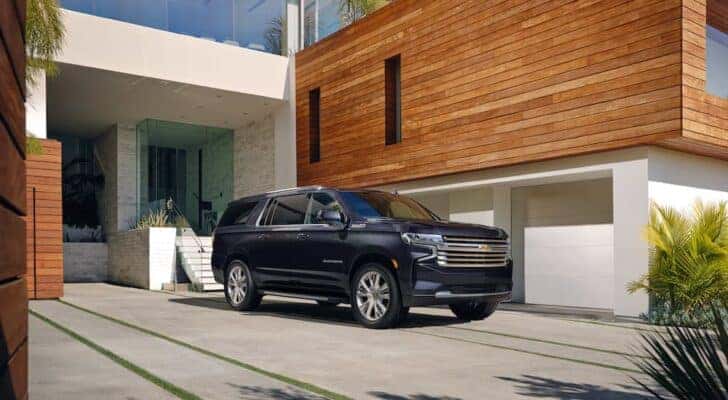 A black 2022 Chevy Suburban is shown from the front at an angle after leaving a dealer that has SUVs for sale.