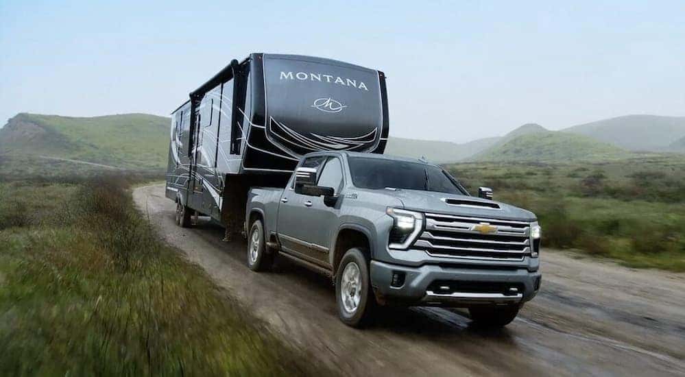 A gray 2024 Chevy Silverado 2500 HD High Country is shown towing a trailer to view trucks for sale in Birmingham.