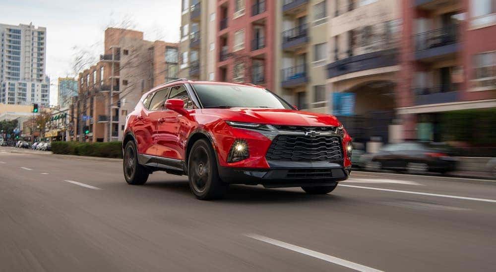 A red 2019 Chevy Blazer RS is shown driving on a city street after visiting a used car dealer.