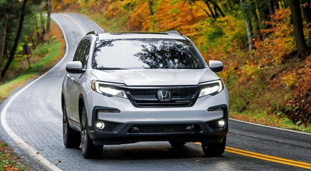 A white 2022 Honda Pilot Black Edition is shown driving on highway.