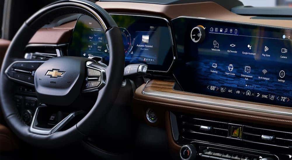 Close-up on the steering wheel in the brown interior of a 2025 Chevy Suburban High Country.