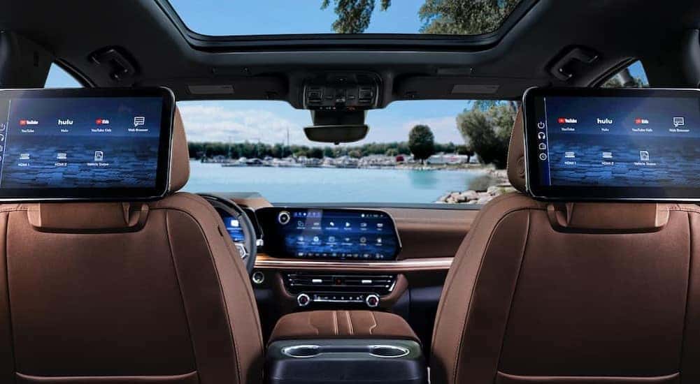 The brown interior and multiple infotainment screens are shown in a 2025 Chevy Suburban.