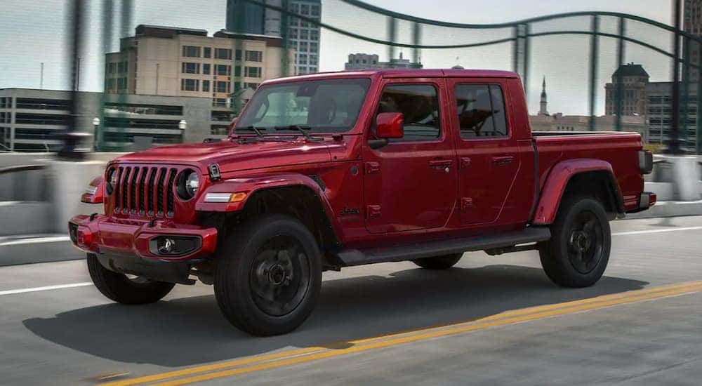 A red 2021 Jeep Gladiator is shown driving on a bridge.