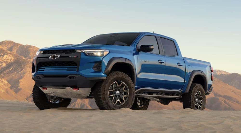 A blue 2023 Chevy Colorado ZR2 is shown parked off-road after searching "used trucks for sale near me."