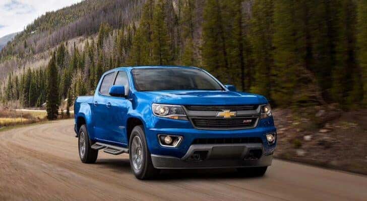 A blue 2020 Chevy Colorado driving on a dirt road.