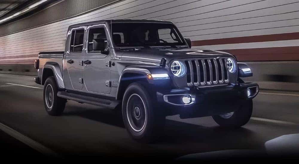 A silver 2023 Jeep Gladiator driving through a tunnel to view used trucks for sale near me.
