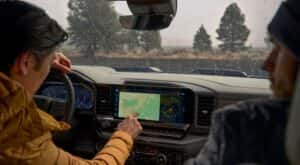 A person operating the dashboard screen in the interior of a 2025 Chevy Silverado 1500.