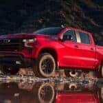 A red 2025 Chevy Silverado 1500 Trail Boss is shown from the front at an angle after leaving a car dealer.