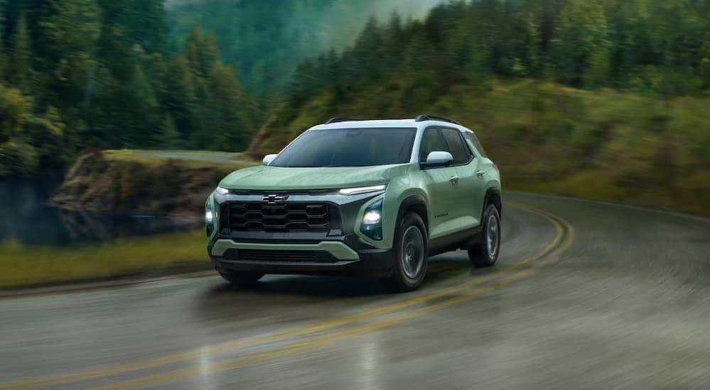 A green 2025 Chevy Equinox for sale driving on a highway.