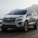 A silver 2025 Chevy Equinox driving down a road.