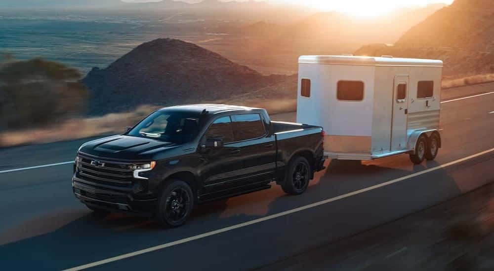 A black 2025 Chevy Silverado 1500 High Country towing a trailer.