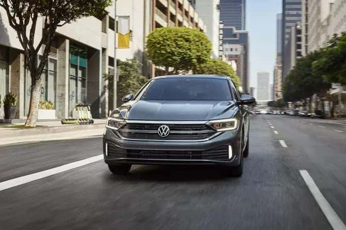 Grey Volkswagen Jetta driving on a city street. 