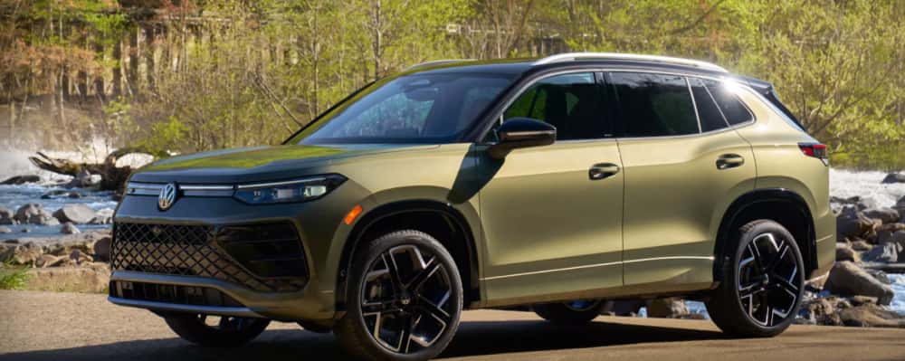 Green Volkswagen Atlas SUV parked near a rocky river