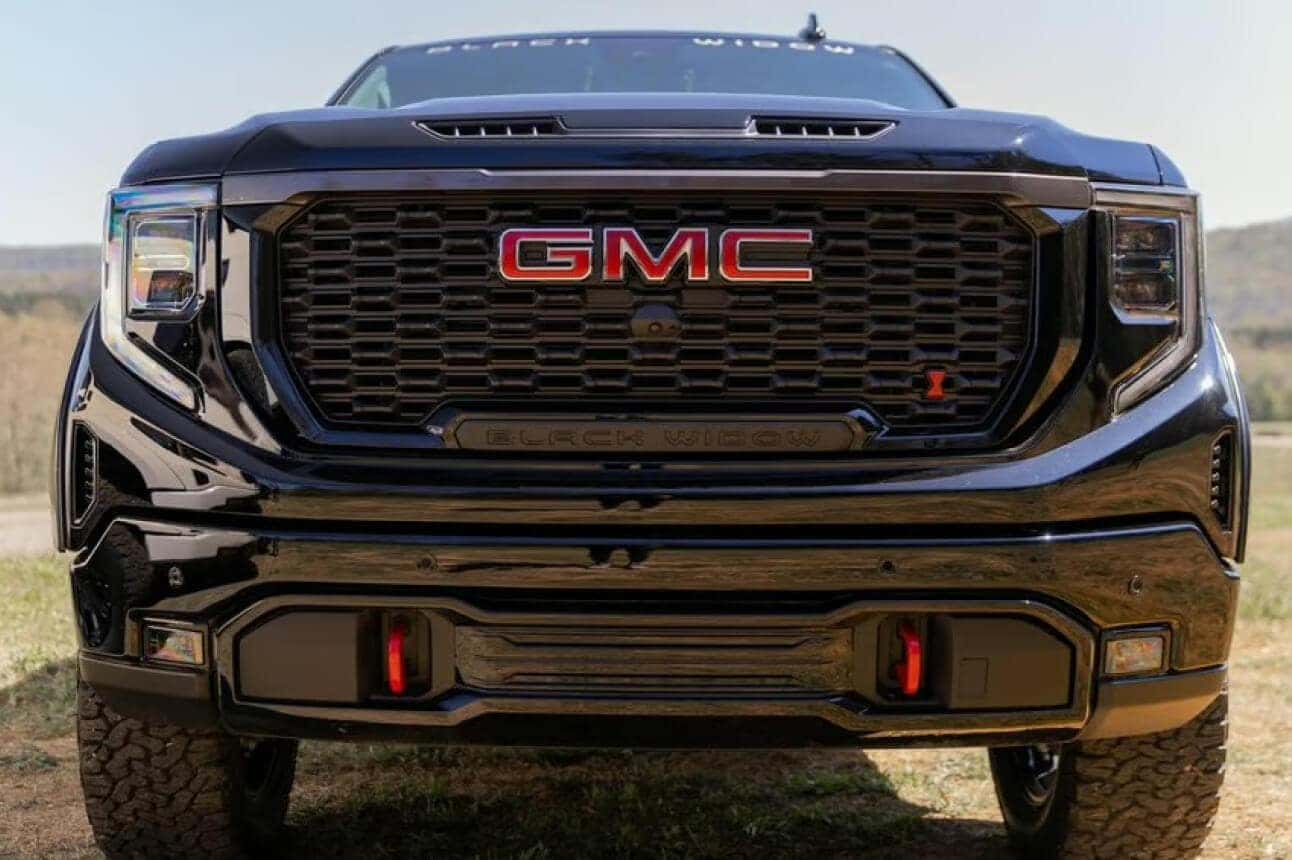 Front close-up view of black GMC Sierra Black Widow grille and bumper outdoors.