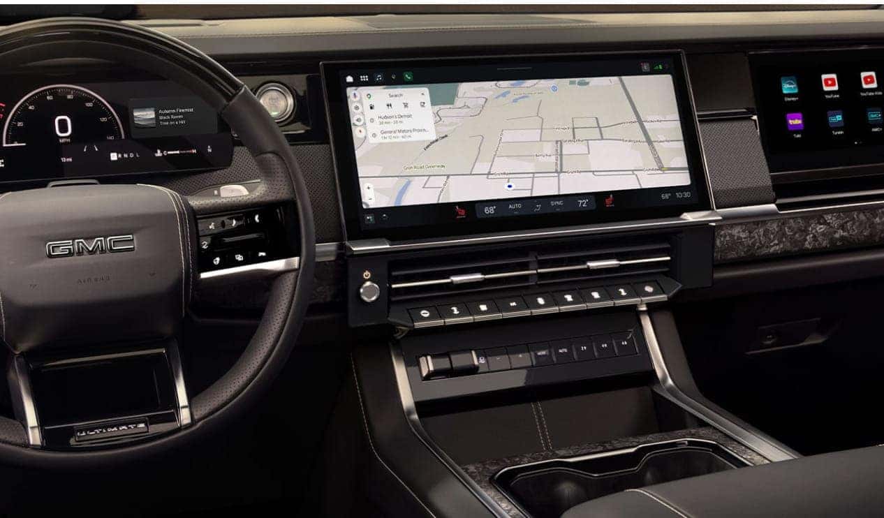 2027 GMC Sierra 1500 interior featuring the GMC-branded steering wheel, digital instrument cluster, and large center touchscreen with navigation displayed.