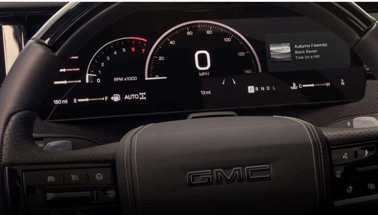 2027 GMC Sierra 1500 digital instrument cluster and GMC-branded steering wheel shown in close-up.