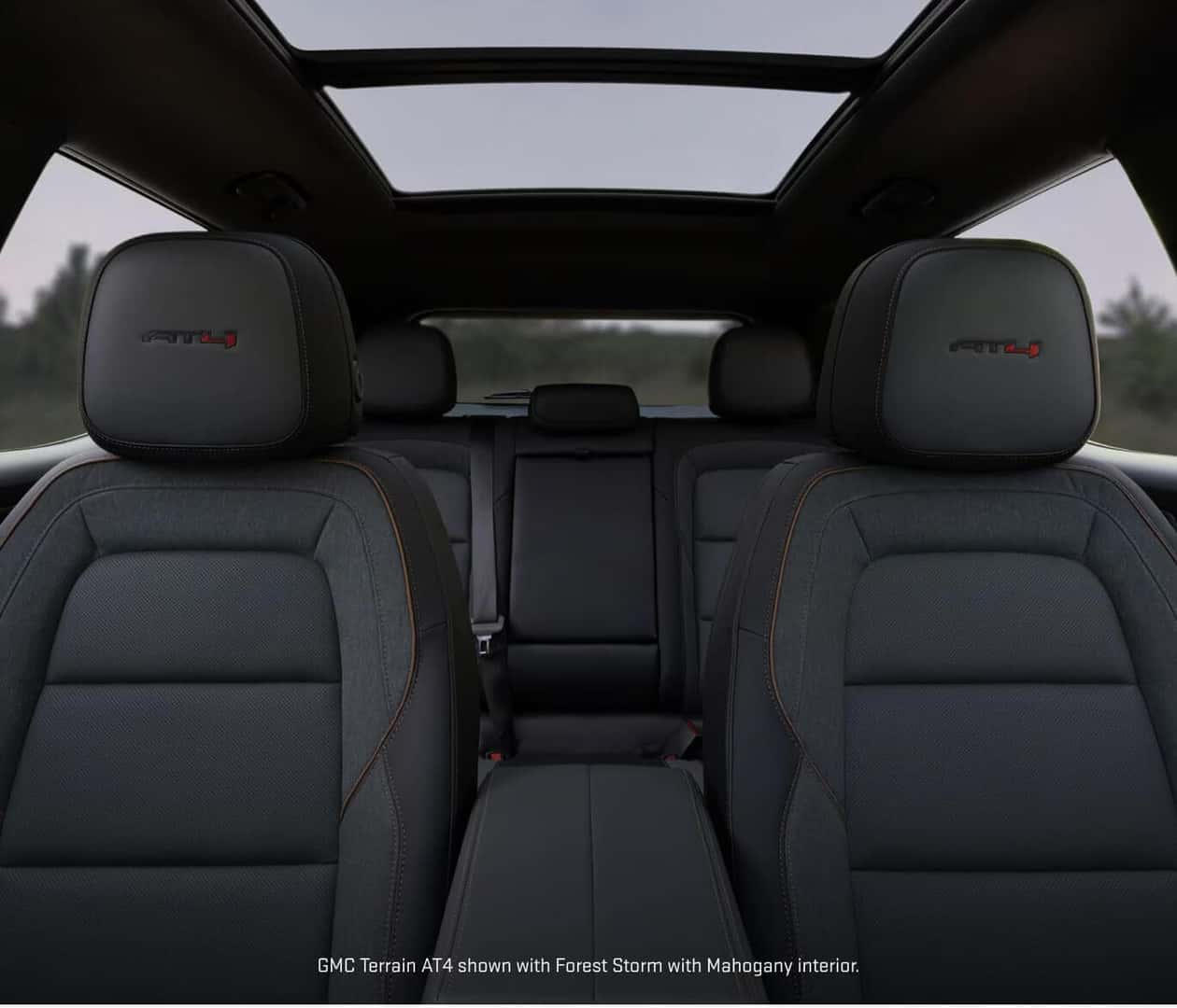 Interior view looking back from the front row of a 2027 GMC Terrain AT4, showcasing Forest Storm with Mahogany accents.