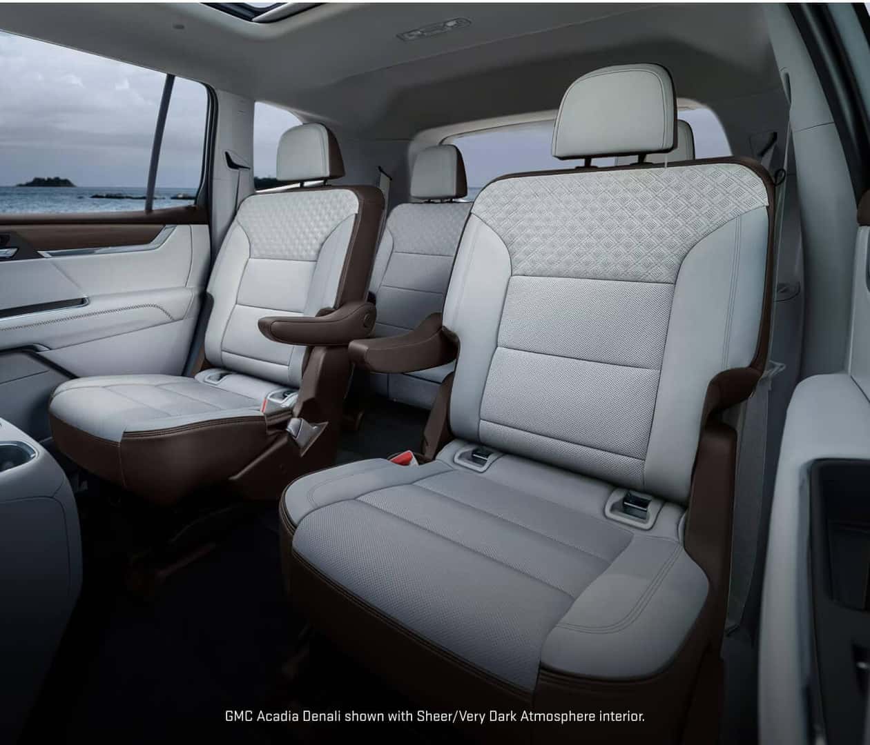 Interior view of the second and third rows in a 2027 GMC Acadia Denali featuring captain's chairs upholstered in Sheer/Very Dark Atmosphere.